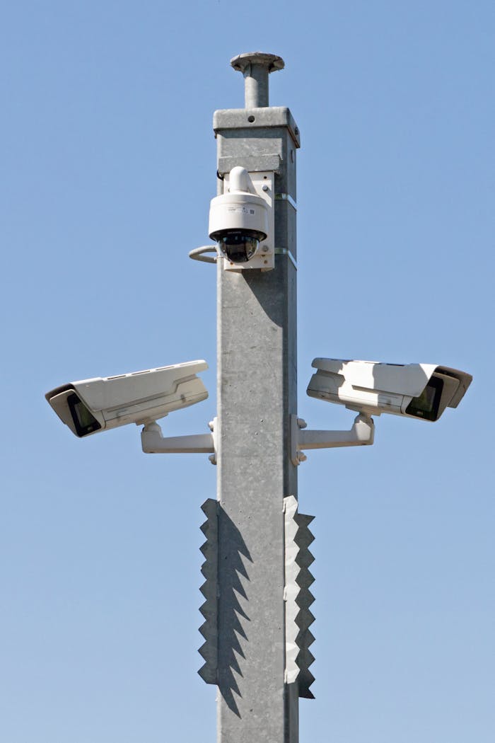 Services Outdoor surveillance system with multiple cameras mounted on a metal pole against blue sky.